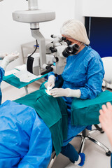 Skilled female surgeon and his medical team performs precise eye surgery on an elderly patient,...