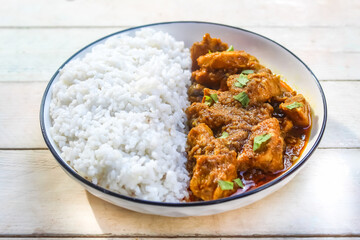 chicken curry with rice in a plate, on a wooden table