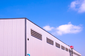 Fototapeta premium Factory industrial building structure with construction worker working on rooftop in construction site against blue sky background, low angle and perspective side view 