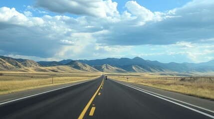 Naklejka premium Endless open road amidst rolling hills under a vast expanse of cloudy skies