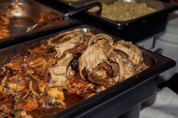 Delicious roast pork ribs served at buffet with cooked vegetables in background