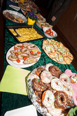 Delicious buffet spread with assorted pastries, sandwiches, and snacks on green tablecloth