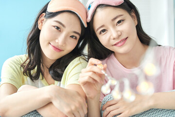 Two Young Women Having Fun at a Pajama Party with Fairy Lights