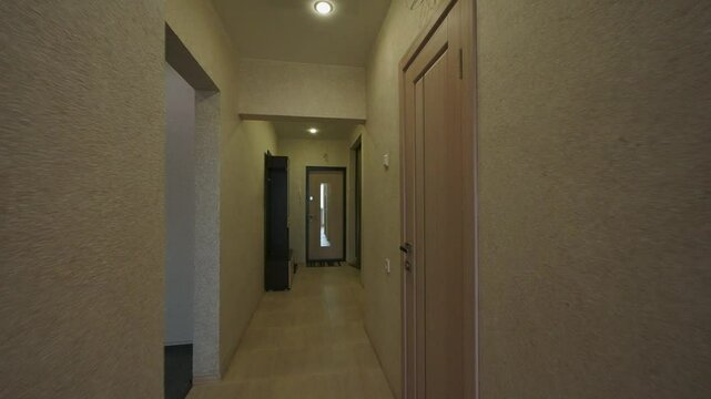 view of a kitchen and hallway, with light wood cabinets and a built-in microwave.