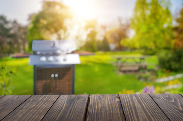 summer time in backyard garden with grill BBQ, wooden table, blurred background
