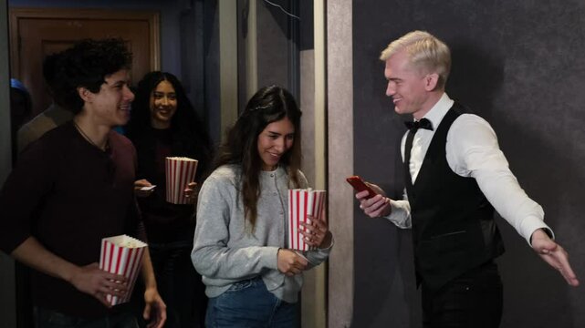 Movie theater employee scanning tickets on smartphone and welcoming people