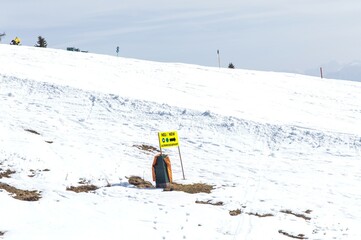 Sunny snowy landscape with safety sign on snow-covered hill