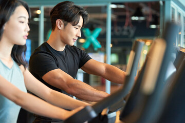 Young Asian Man and Woman Exercising Together at Gym