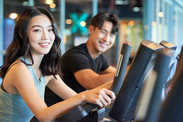 Young Asian Man and Woman Exercising Together at Gym