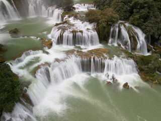 Obraz premium Multiple Tiered Waterfalls in a Lush Green Landscape