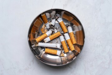 Image of stubbed out cigarette butts in metal ashtray, on marble background, tobacco smoking, ash in silver pot.