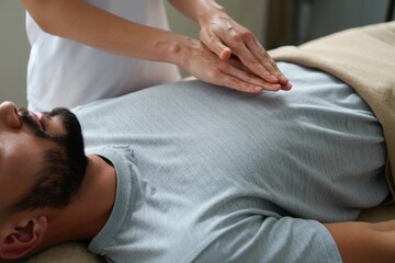 close-up view of bearded man receiving reiki healing session above stomach and chest