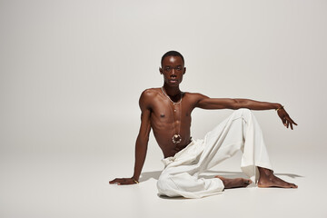 Stylish young african american man posing confidently in vibrant white attire under studio lighting