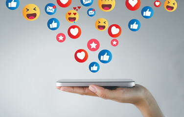 Smartphone on hand flipping with Floating Social Media Reactions Icons on Light Background idea for social media,online engagement,digital communication,online feedback.