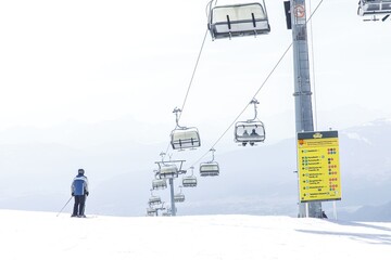 Lone skier on snowy mountain with chairlift in bright daytime scene