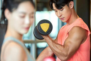 Obraz premium Asian Woman and Man Lifting Weights at Gym