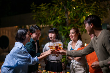 A group of people are gathered around a table, raising their glasses to toast