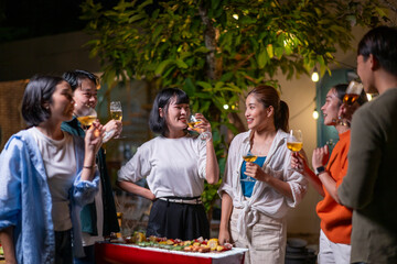 A group of people are gathered around a table with food and drinks