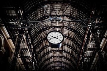Hanging station clock beneath an arched metal ceiling
