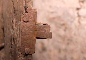 Rusty metal latch on weathered wooden door in close-up detail