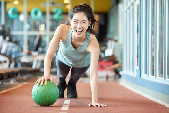 Young Asian Woman Exercising with Medicine Ball in Gym