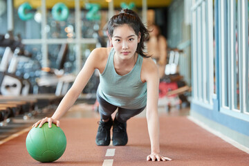 Fototapeta premium Young Asian Woman Exercising with Medicine Ball in Gym