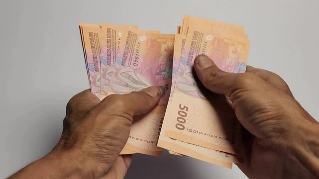 A man is counting 5,000 rupiah banknotes.