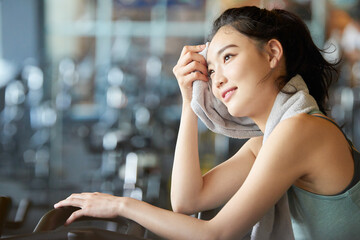 Asian Woman Resting on Exercise Bike at Gym