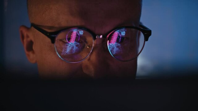 Male scientist working on a computer in a futuristic research laboratory. computer screen displaying an inflammation point in a neck reflecting in glasses