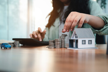 Young woman is calculating and planning her savings to buy house and car in the future. Financial...