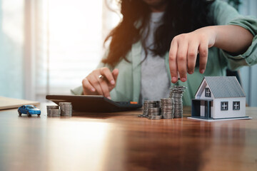 Young woman is calculating and planning her savings to buy house and car in the future. Financial...