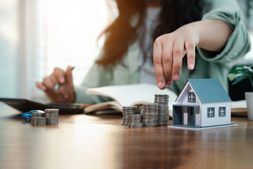 Young woman is calculating and planning her savings to buy house and car in the future. Financial...