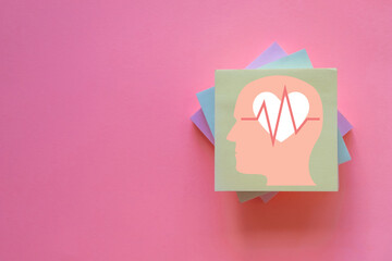 Sticky note with heartbeat and brain icon over pink pastel background.,Mental health,emotional well-being,health awareness,health care,emotional awareness,self-care concept.