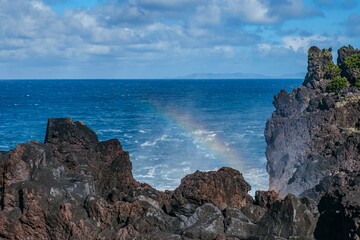 Volcanic Coastline with Rainbow Over the Atlantic Ocean. Natural Lava Rocks and Sea Spray, with a...