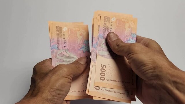 A man is counting 5,000 rupiah banknotes.