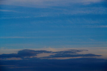 Altostratus clouds in the evening sky illuminated by the rays of the setting sun, close-up, cloudy background, pastel tones of the evening sky, clouds in the evening sky.