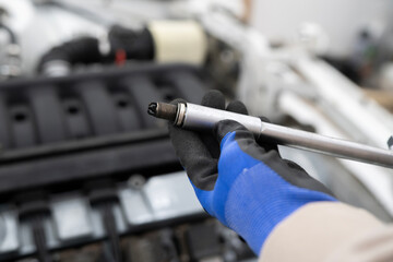 Fototapeta premium Car Mechanic Utilizes Spark Plug Wrench for Efficient Engine Maintenance in a Professional Workshop Setting