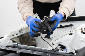 Car Mechanic Working With Ignition Coil in an Automotive Garage, Focused on Engine Repair
