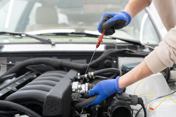 Mechanic uses a dipstick to check engine oil levels under the hood, ensuring vehicle operates efficiently and safely during maintenance checks.