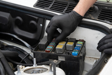 Expert Car Mechanic Inspecting and Replacing Fuses in a Vehicle's Fuse Box at an Auto Repair Shop