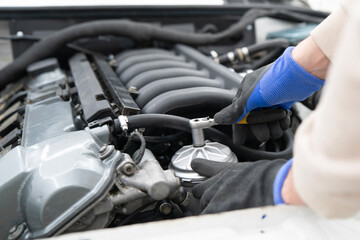 Mechanic works diligently with a ratchet wrench on engine parts in a busy auto shop, focusing on repairs and maintenance tasks.
