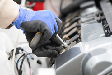 Obraz premium Mechanic works diligently with a ratchet wrench on engine parts in a busy auto shop, focusing on repairs and maintenance tasks.