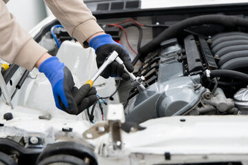 Mechanic works on a vehicle's engine, detailed repairs taking place in a well-lit auto repair shop setting.