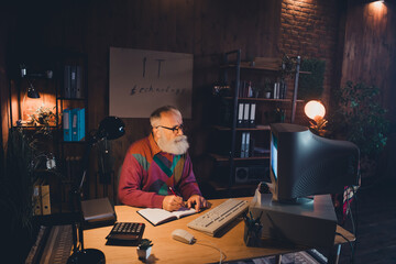 Mature technology specialist working on programming in a cozy home office with vintage decor and...