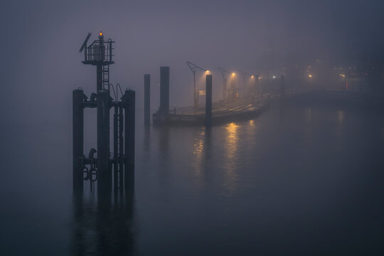 Foggy night view of a harbour in HafenCity, Hamburg, Germany with illuminated pier and water reflections. - Powered by Adobe