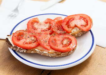Two bruschettas with tomato slices on a plate