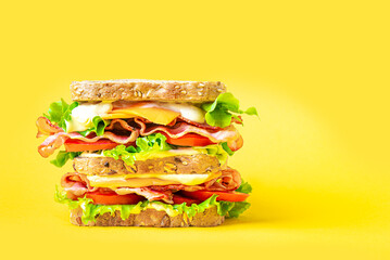 Double bacon, lettuce, tomato sandwich with cheese on yellow