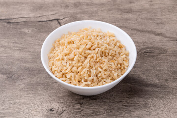 Cooked brown whole rice in a bowl over wooden table
