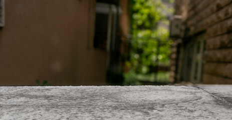 Close-up rough concrete table-top out door in bokeh. Stone or concrete, shot with shallow depth of field with garden. Natural texture outdoor for backgrounds or design use for copy space.