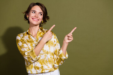 Fototapeta premium Young businesswoman in casual outfit pointing with joy, khaki background